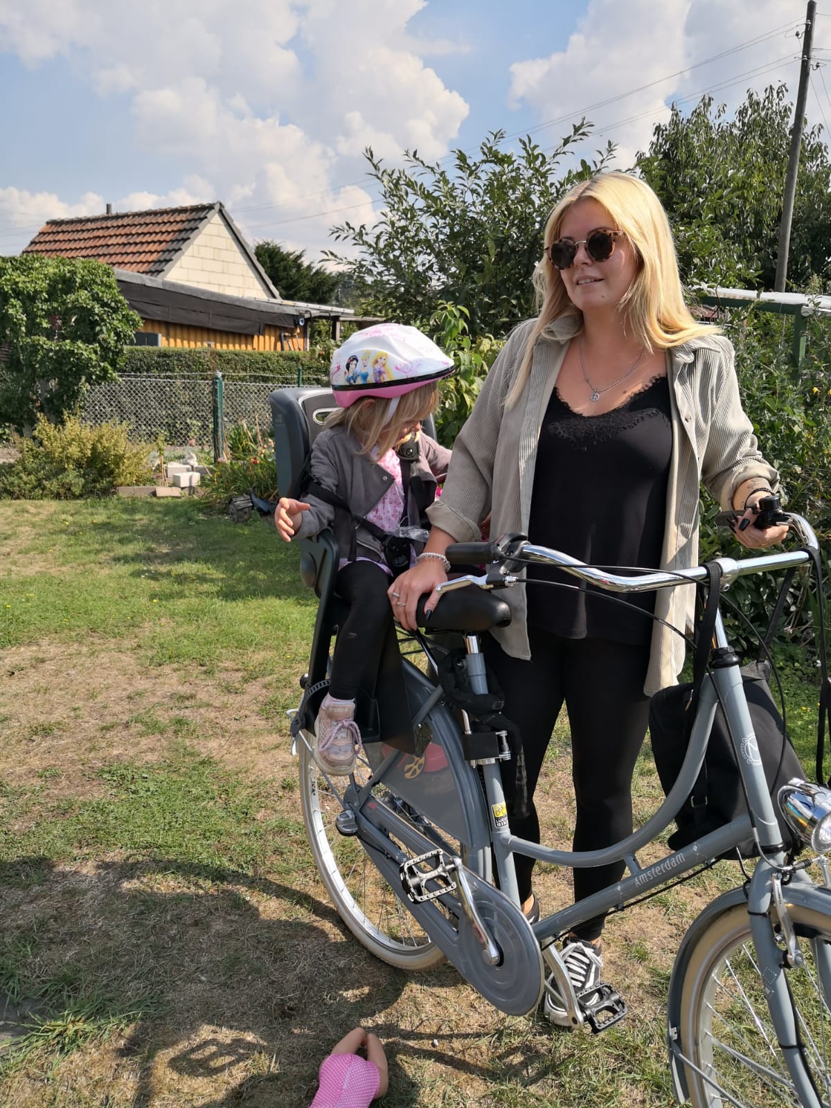 Frau (Mutter?) mit dem Fahrrad mit Kind sitzen halten